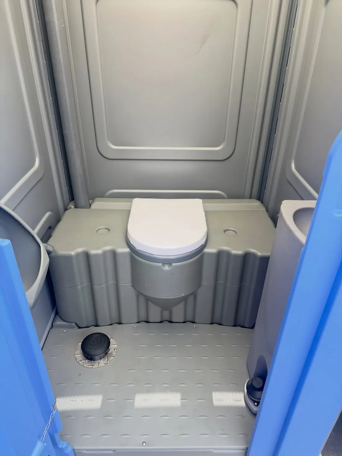 Inside a deluxe flushing porta potty with toilet lid and flush pedal