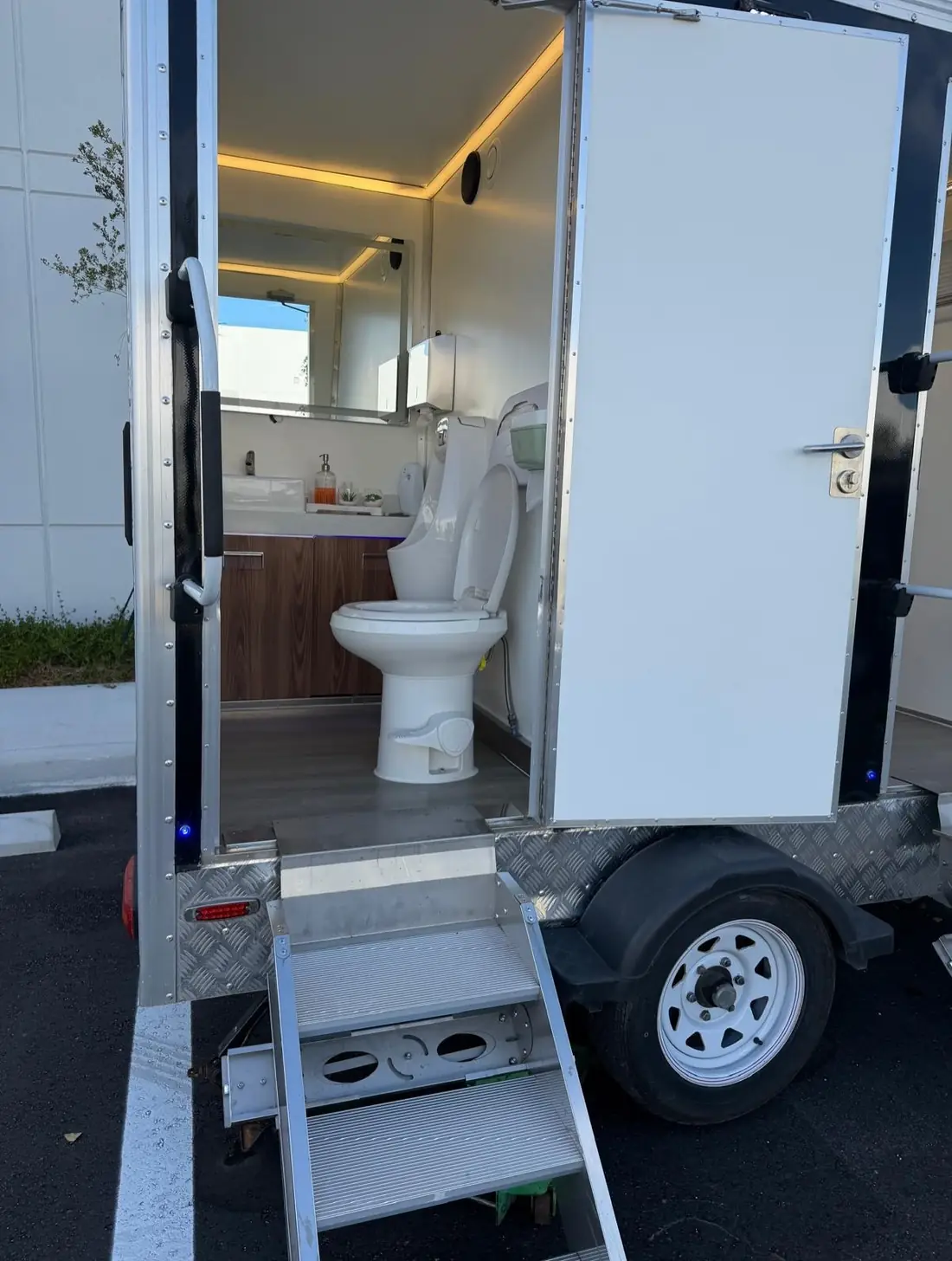 Restroom trailer stall with flushing toilet, vanity and mirror